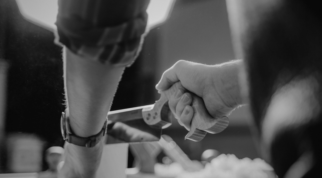 photo en noir et blanc d'une action de découpe de bois à la scie à main dans notre atelier